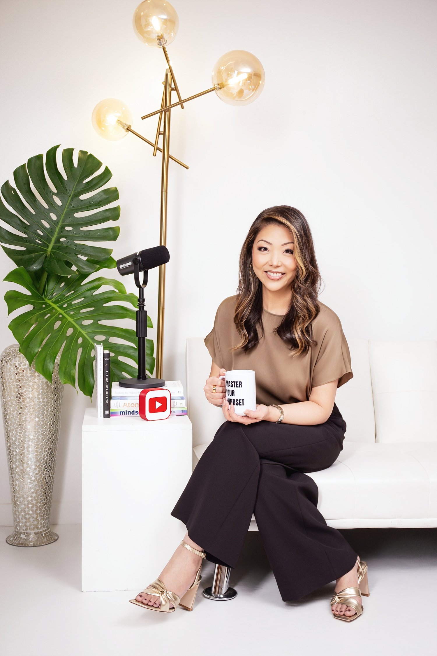 Chenise Kanemoto in her recording space with a microphone, mindset mug, and YouTube play symbol